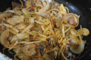 In a wok, add oil and garlic.  Add Korean crushed chili peppers.  The oil will start to turn red and become more aromatic.  Add onions and seafood.  